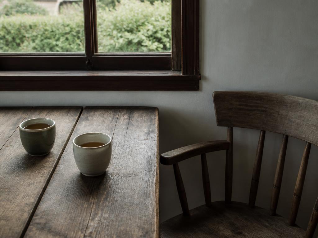 Two cups of tea on a weathered wooden table beside a window